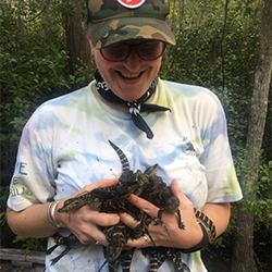 Kimberly Andrews holds several juvenile alligators in her arms.