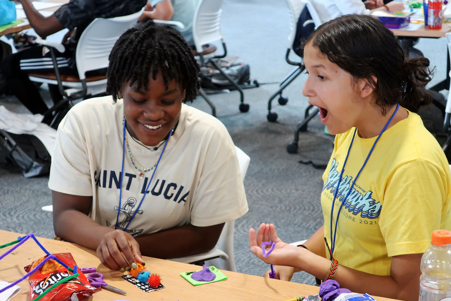 two high school students are excited to participate in an activity using craft supplies