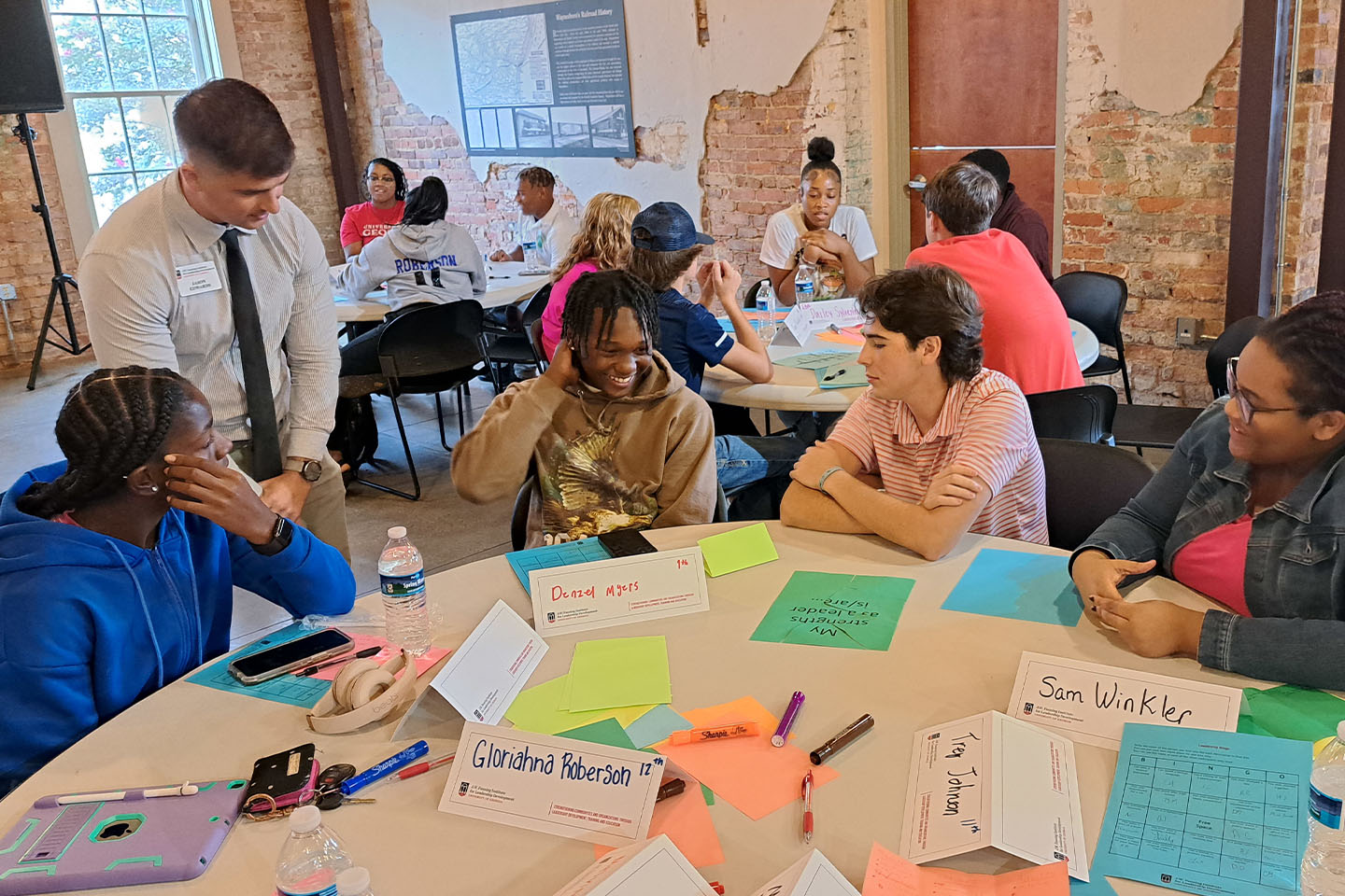 man works with 4 students on a colorful leadership activity