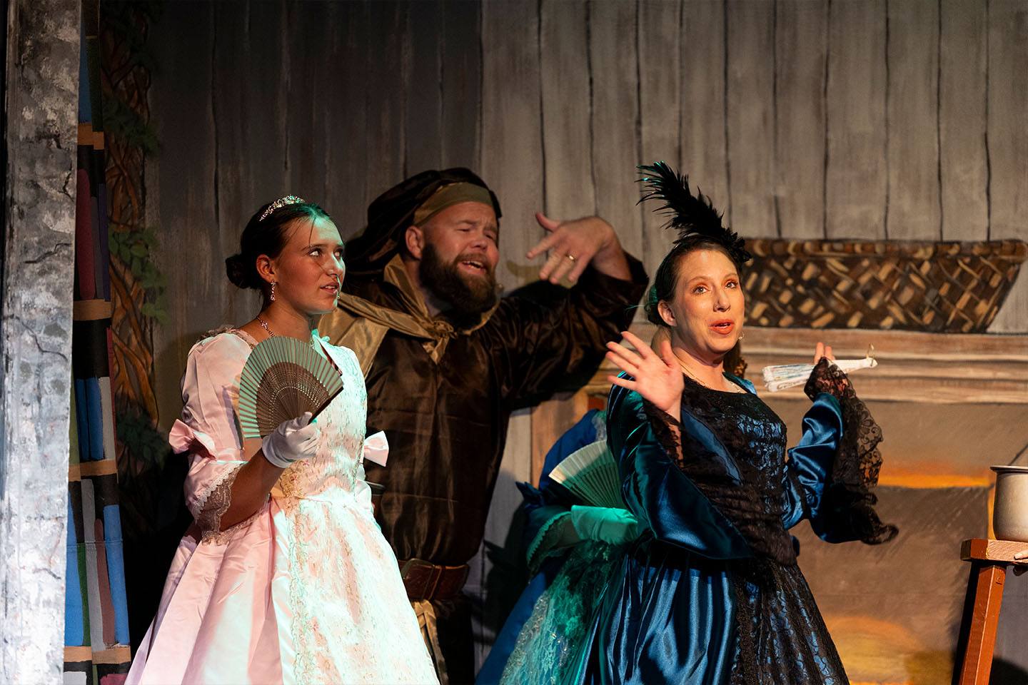 three actors perform on a stage in historical costumes