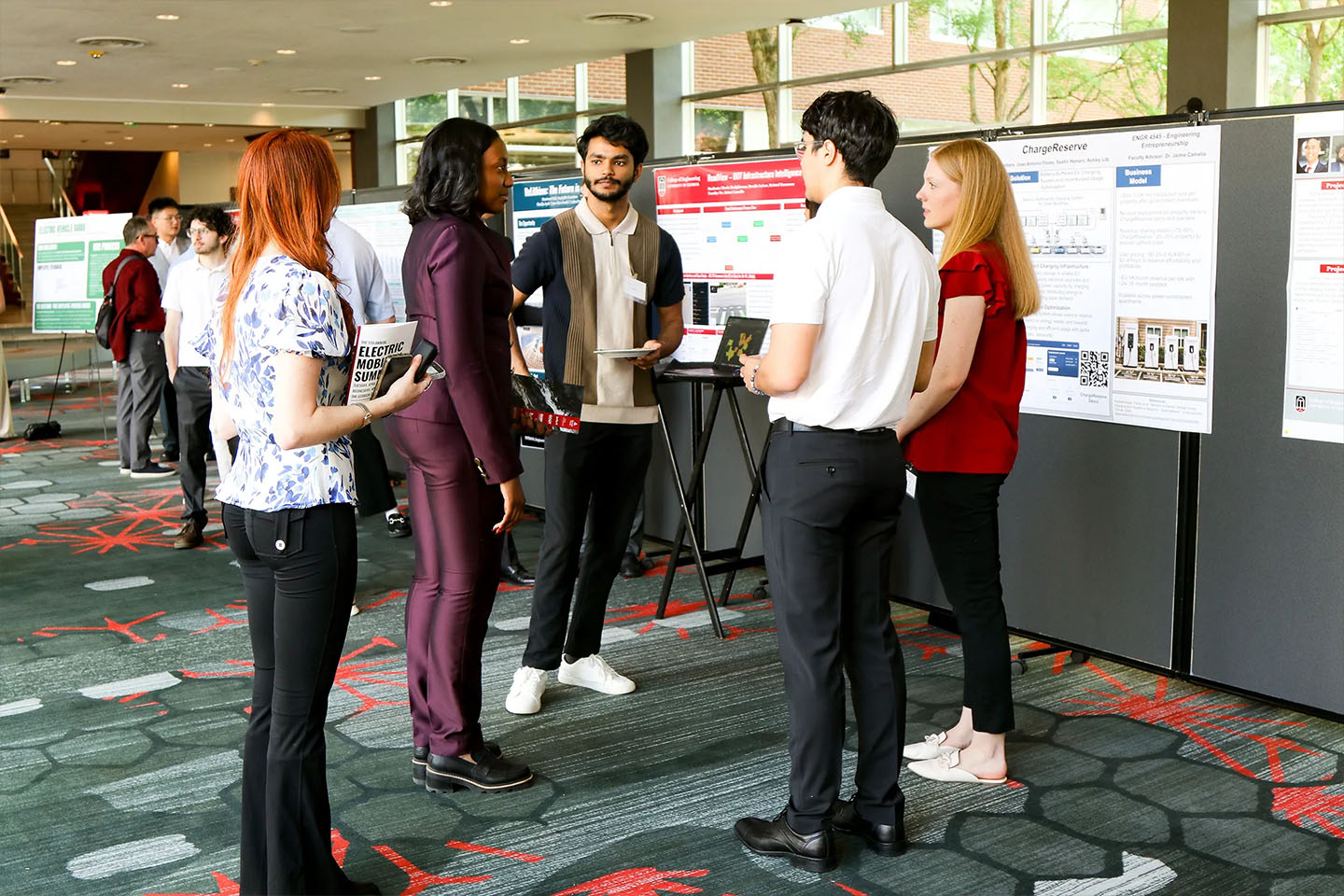 students at conference talk in front of posters